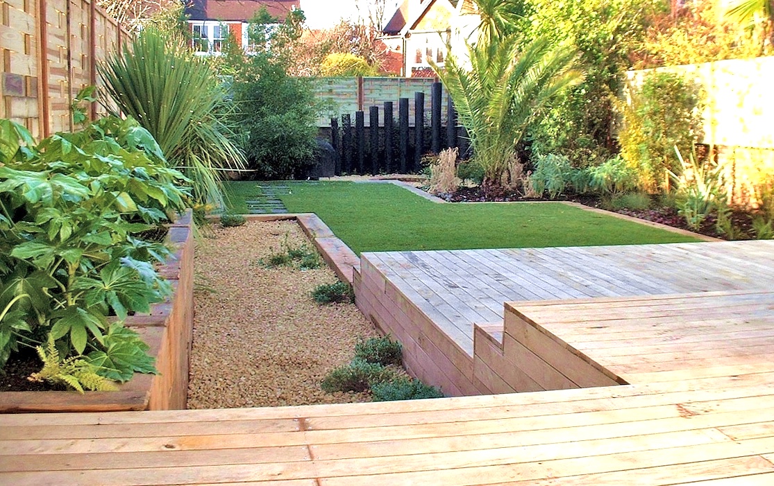 A large oak deck has steps leading down to a lawn design based on two offset squares in this large town garden in Hove, Sussex. The exotic tropical plants are dominant even in mid-winter.